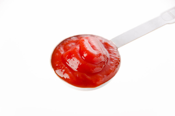 Measuring spoon of tomato sauce on white background - Photo, Image
