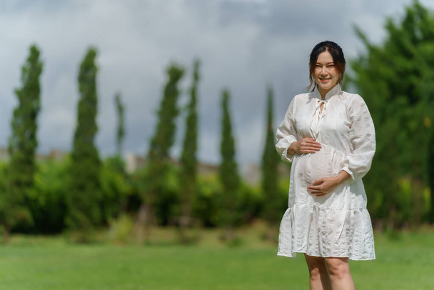 happy pregnant woman standing in the park - Foto, imagen
