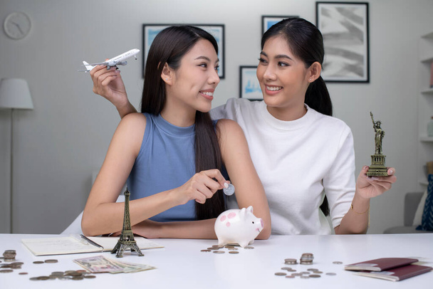Fiatal ázsiai leszbikus pár azt tervezi, hogy pénzt takarít meg egy világkörüli útra. Utazási költségvetés koncepció. útlevél, emlékmű modell és repülőgép játék a képen. Párkapcsolati életstílus. - Fotó, kép