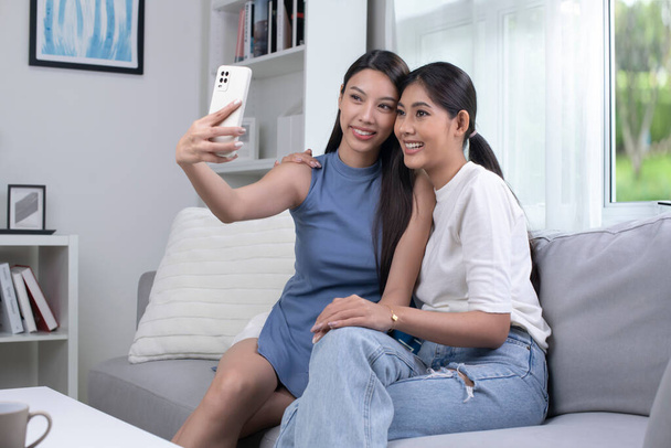 Mutlu genç Asyalı lezbiyen çift oturma odasında selfie çekiyor. LGBT çift yaşam tarzı konsepti. - Fotoğraf, Görsel
