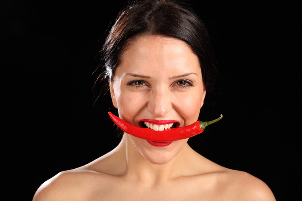 Beautiful woman biting on red chili pepper - Foto, afbeelding