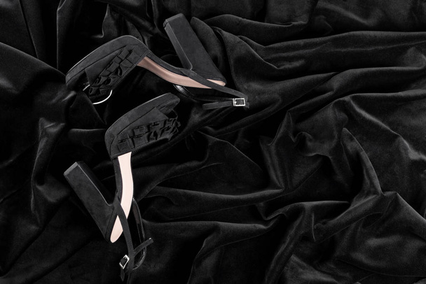 Sapatos de salto alto de veludo preto feminino deitado em um tecido preto, o conceito de moda e estilo - Foto, Imagem
