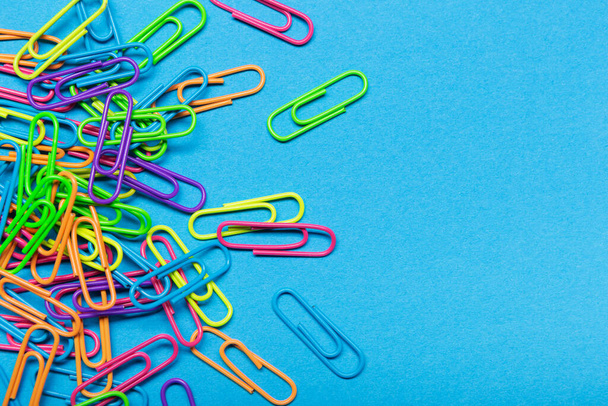 a bunch of multi-colored paper clips scattered on a blue background, office concept, copy space - Photo, image