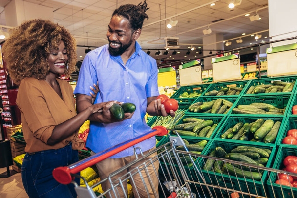 African american couple shopping for healthy fresh food at produce section of supermarket. - Foto, imagen
