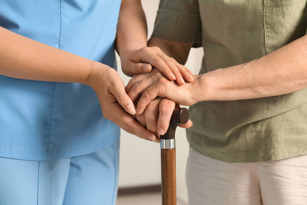 Elderly woman with walking cane and female caregiver indoors, closeup - Photo, image