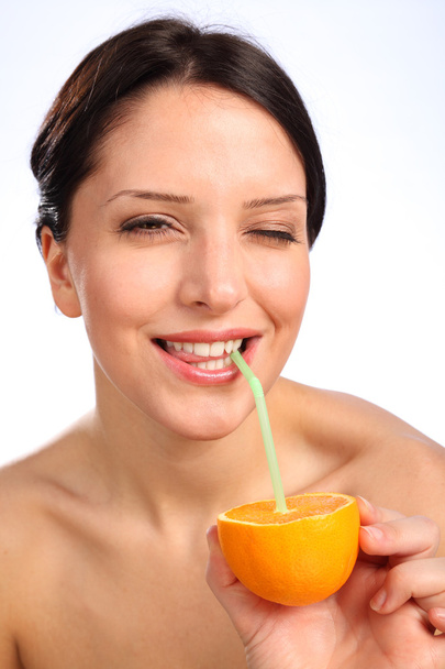 Beautiful young woman drinking juice from orange - Фото, изображение