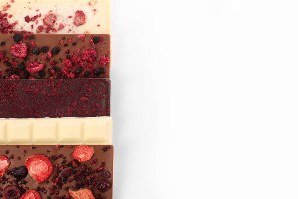 Chocolate bars with freeze dried berries on white background, flat lay. Space for text - Fotó, kép