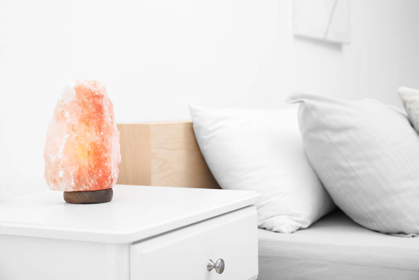 Гімалайський соляний ліхтарик на білому ночному столику в спальні. Простір для тексту - Фото, зображення