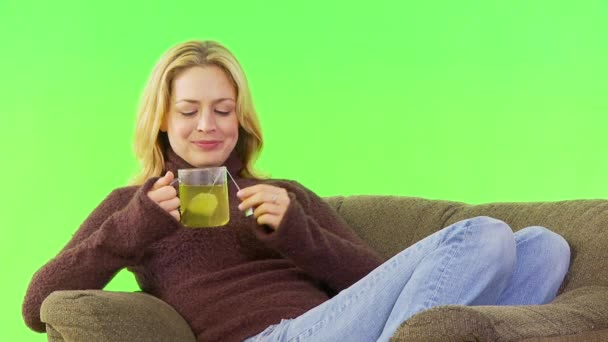 Mujer empapando y bebiendo té en su sofá - Imágenes, Vídeo