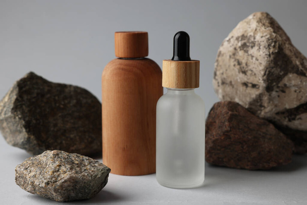 Different bottles and stones on grey background, closeup - Foto, immagini