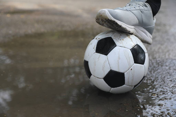 Man with soccer ball near puddle outdoors, closeup. Space for text - 写真・画像