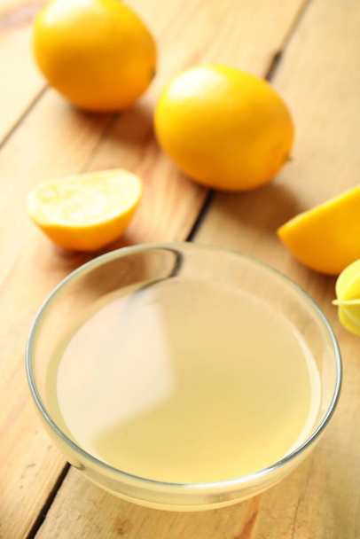 Freshly squeezed lemon juice in bowl on wooden table - Valokuva, kuva