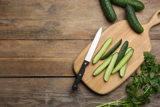 Fresh ripe cucumbers and parsley on wooden table, flat lay. Space for text - Foto, Imagen