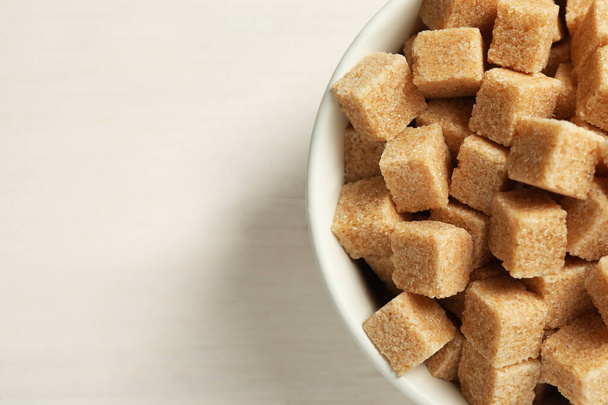 Brown sugar cubes on white wooden table, top view. Space for text - Fotó, kép