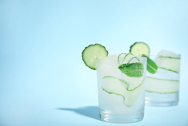Tasty fresh cucumber water with mint on light blue background, space for text - Foto, afbeelding