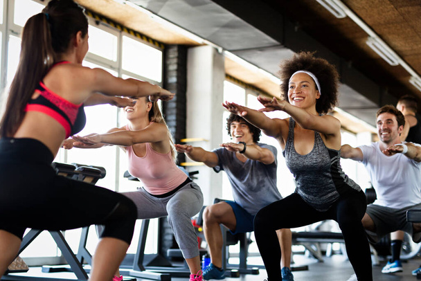 Multiethnic group of people training in a gym. Trainer and sportive fit persons exercising in a fitness class - Foto, immagini
