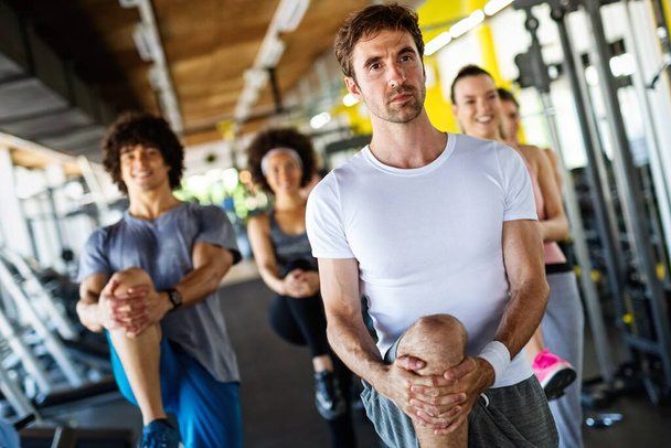 Multiethnic group of people training in a gym. Trainer and sportive fit persons exercising in a fitness class - Foto, imagen