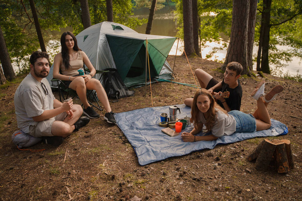 Foto de cuatro amigos haciendo senderismo y acampando juntos en los bosques de verano durante el día. - Foto, imagen