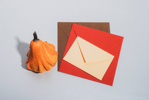 Los sobres coloridos y la calabaza sobre la mesa. Concepto de otoño. Vista superior, maqueta. - Foto, Imagen