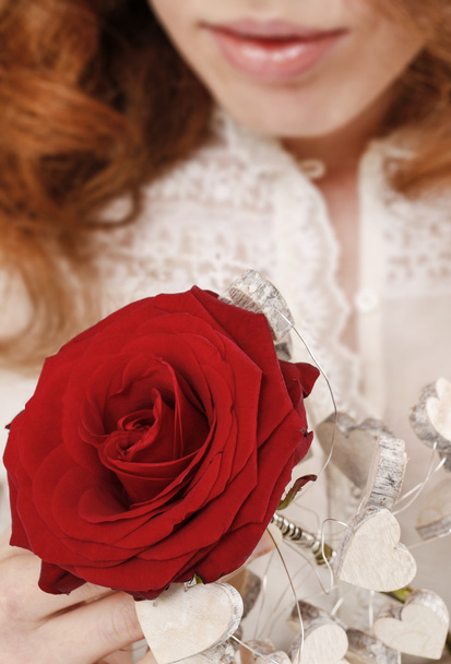 Woman holding red rose decorated with wooden hearts - Foto, Imagen