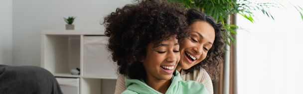 happy african american preteen girl and curly mother looking down, banner - Foto, imagen