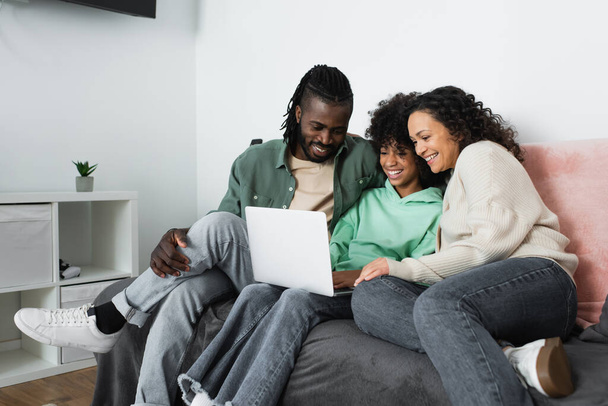 happy african american family watching comedy movie on laptop in living room  - Zdjęcie, obraz