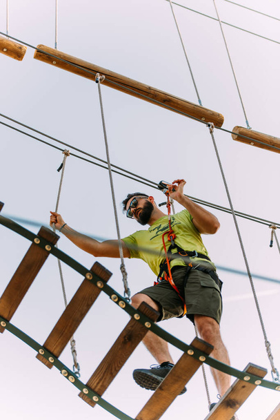 Schöner Mann balanciert auf Leiter im Erlebnispark - Foto, Bild