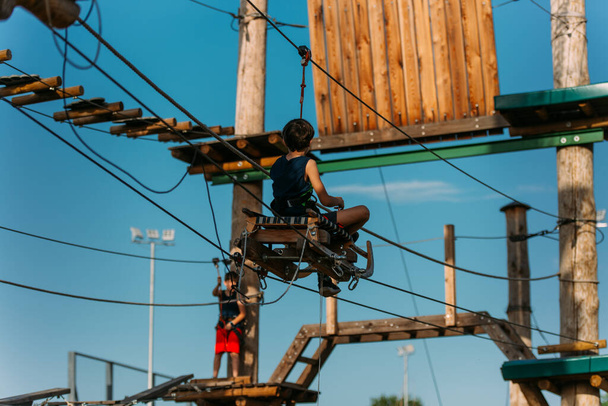 Молодий маленький хлопчик катається на санях на мотузках в парку пригод
 - Фото, зображення