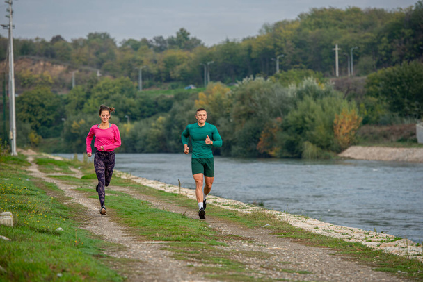 Two fit and attractive friends are doing some morning run by the river - Photo, Image