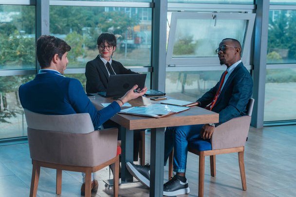 Багатонаціональні бізнесмени обговорюють за конференц-столом в офісі
 - Фото, зображення