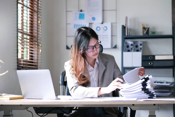 asian beautiful business woman writing paper. busy female professional employee write on paper sheet plan for other worker. an exhausted focus woman plan business by writing paper notes on the desk - Photo, Image