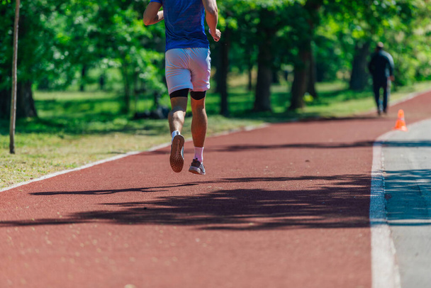 Retrospectiva de un joven atleta corriendo al aire libre en la pista de carreras - Foto, imagen