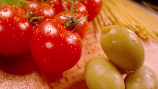 スーパースローモーション、クローズアップ、プローブレンズ:新鮮な赤いおいしいトマトと緑のオリーブのクローズアップ。水滴の中の野菜のスローモーションビュー。パスタのための健康的な成分のプローブレンズショット. - 映像、動画