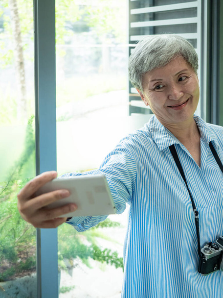 Πορτρέτο της ευτυχούς ηλικιωμένης γυναίκας της Ασίας 60 λήψη selfie φωτογραφία χρησιμοποιώντας κάμερα smartphone για την έννοια του ταξιδιού. - Φωτογραφία, εικόνα