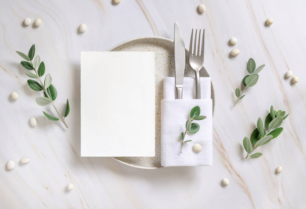 Elegant Table setting with card and envelope decorated with eucalyptus branches  top view, Wedding Mockup. Romantic table with vertical paper card. Close to nature and simplicity concepts - Foto, Imagen