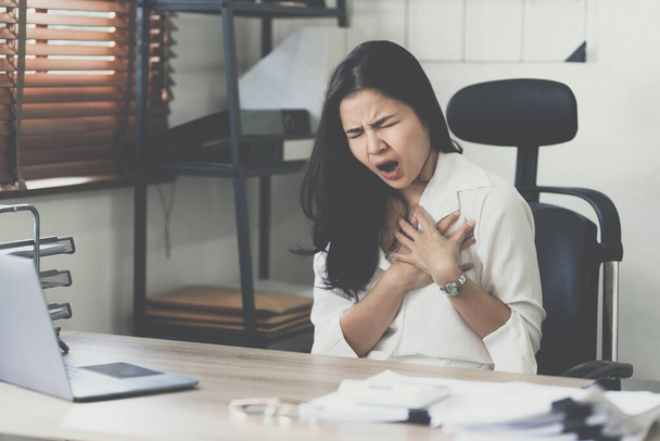 Young business woman working in office suffering from heart attack - Foto, Imagem