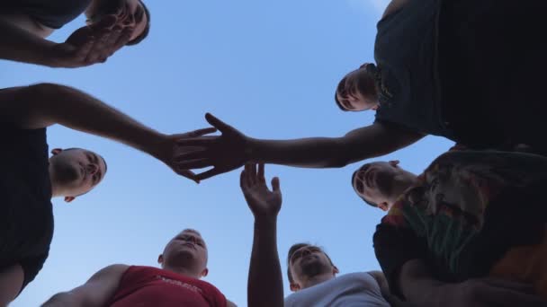 Mladí sportovci skládají ruce jeden po druhém v jednotě. Skupina nejlepších přátel položila ruce doprostřed kruhu a zvedla je k modré obloze. Koncept přátelství a týmové práce. - Záběry, video