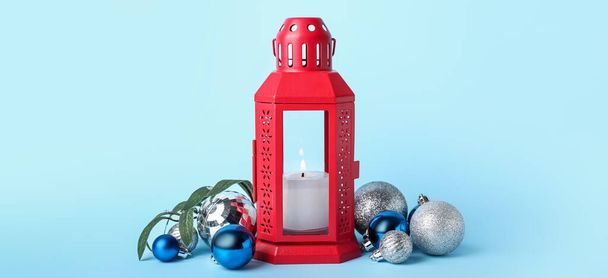 Christmas lantern with burning candle and decor on light blue background - Foto, immagini