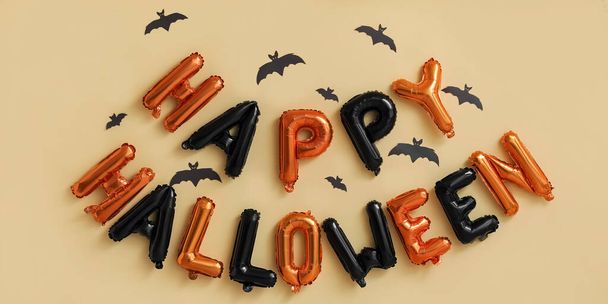 Text HAPPY HALLOWEEN z balónů a papírových netopýrů na béžovém pozadí - Fotografie, Obrázek