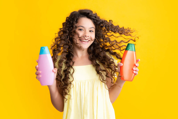 Child with shampoo conditioner. Daily cosmetic care. Teenager kid 12, 13, 14 years old hold bottle of hair and skin care. Beauty health and cosmetics. Excited teenager, glad amazed emotions - Fotó, kép