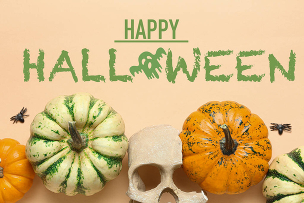 Pumpkins, skull and text HAPPY HALLOWEEN on beige background - Photo, image