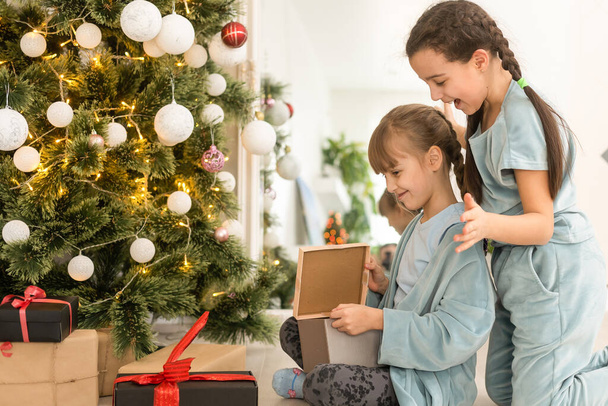 Due bambine amiche con regalo vicino all'albero di Natale - Foto, immagini