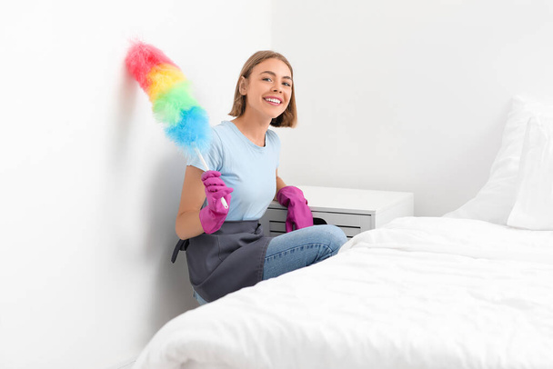 Young housewife with duster in bedroom - Photo, image