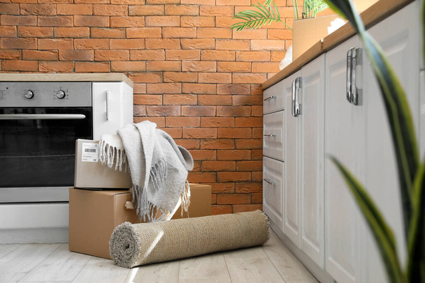 Картонные коробки с клеткой и ковром на кухне в день переезда - Фото, изображение