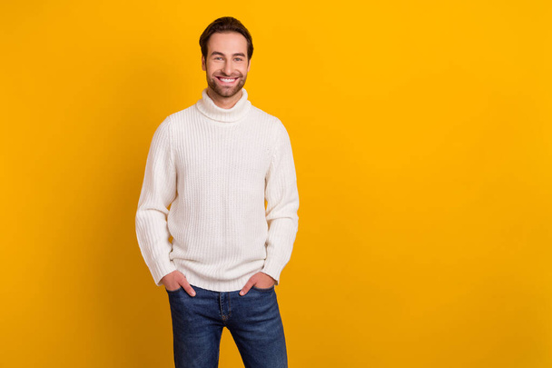 Foto van vrolijke aantrekkelijke man handen zakken genieten van nieuwe outfit dragen witte trui geïsoleerde gele kleur achtergrond. - Foto, afbeelding