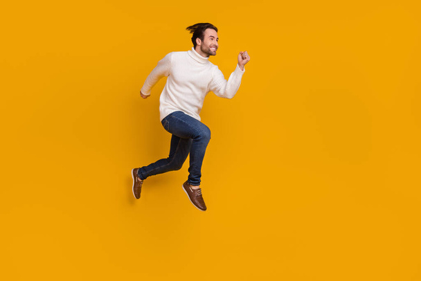 Photo of attractive sweet guy wear white pullover jumping high running fast isolated yellow color background. - Fotografie, Obrázek