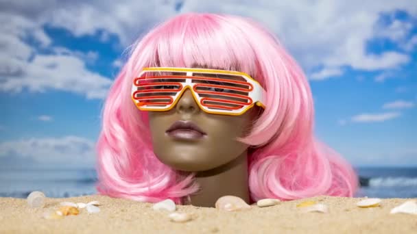Una cabeza de maniquí femenino de plástico atascado en la arena mirando a su alrededor en una hermosa playa - Metraje, vídeo