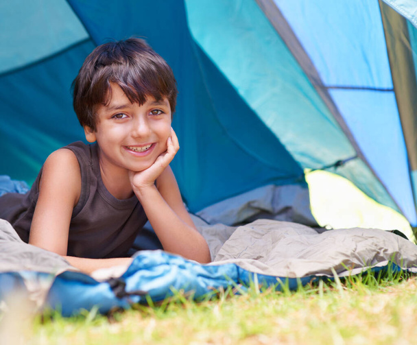 S'imaginant être le prochain Bear Grylls... Portrait d'un jeune garçon allongé dans sa tente en campant - Photo, image
