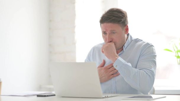 Middle Aged Man Coughing while using Laptop in Office - Fotó, kép