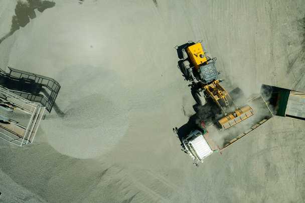 zicht vanuit de lucht op zandladers scheppen rotsen in vuilniswagen - Foto, afbeelding